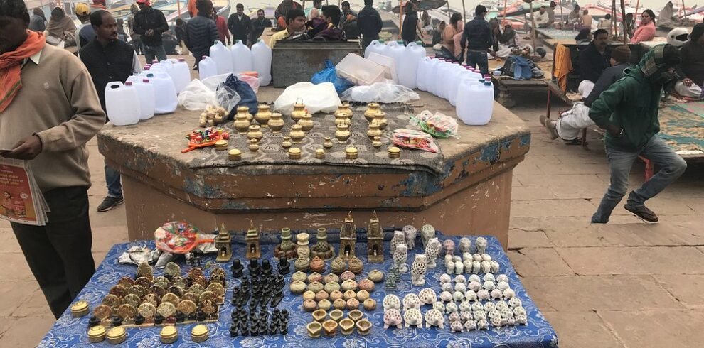 Street market stall in Varanasi selling brass diyas, conch shells, and Ganga water containers near the ghats