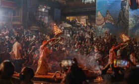 Priests performing Ganga Aarti with flames at the banks of the Ganges River in Varanasi during sunset